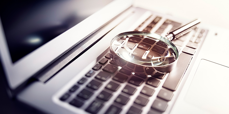 Magnifying glass on laptop keyboard search for online documents background