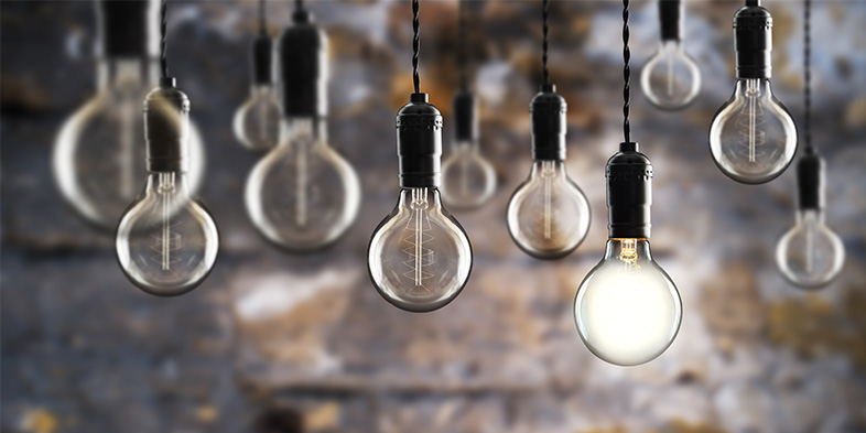 Lightbulbs surrounding single lit lightbulb